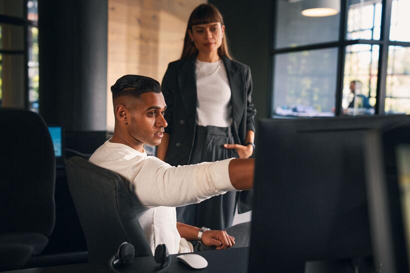 Ein Mann und eine Frau im Büro diskutieren, er zeigt etwas