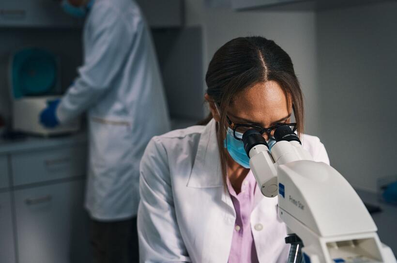 Woman with white coat at the microscope