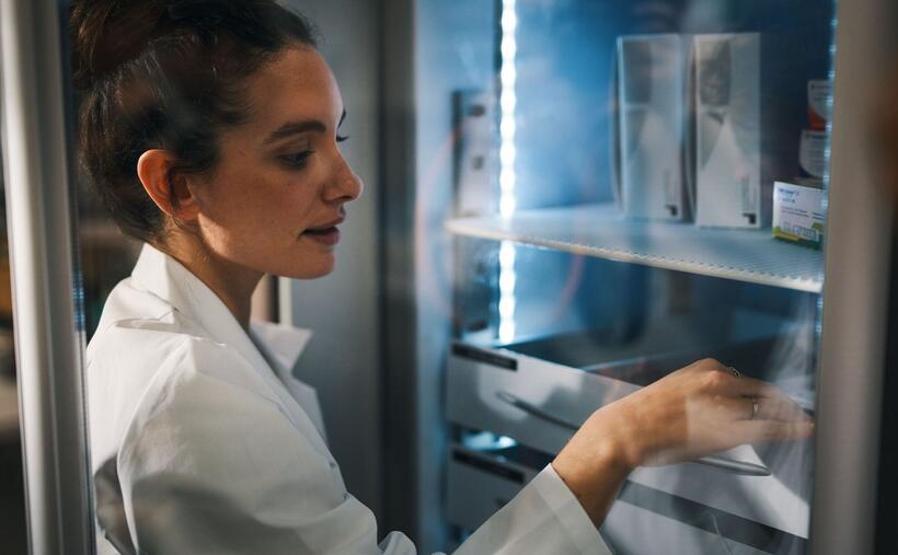 Une femme sort un médicament du réfrigérateur